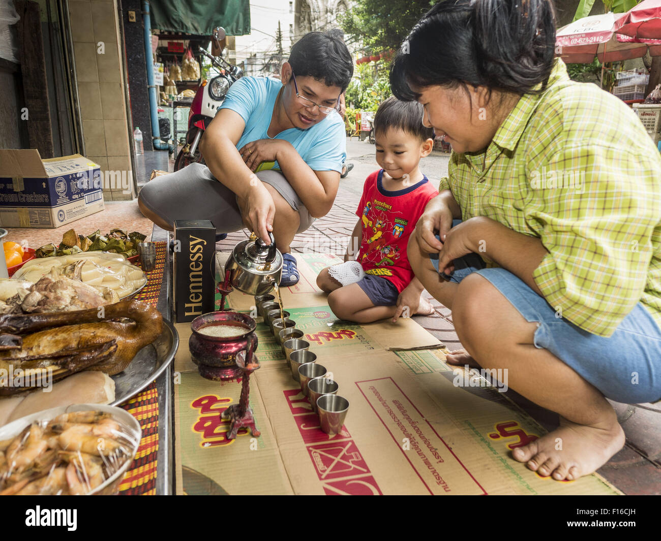 Bangkok, Bangkok, Thailand. 28. August 2015. Frauen Tee gießen und verlassen ein Bankett der Nahrung für ihre Vorfahren auf Hungry Ghost-Tag in Bangkoks Chinatown. Mahayana-Buddhisten glauben, dass die Pforten der Hölle werden auf den Vollmond des siebten Mondmonats des chinesischen Kalenders geöffnet, und die Geister der hungrigen Geister die Erde durchstreifen durfte. Diese Geister müssen essen und Verdienst zurecht zu finden zurück zu ihren eigenen. Menschen helfen, indem Nahrung, Papiergeld, Kerzen, Blumen, machen dabei eigenen Verdienst. Hungry Ghost-Tag ist in Gemeinden mit einem großen ethnischen chinesischen Popul beobachtet. Stockfoto