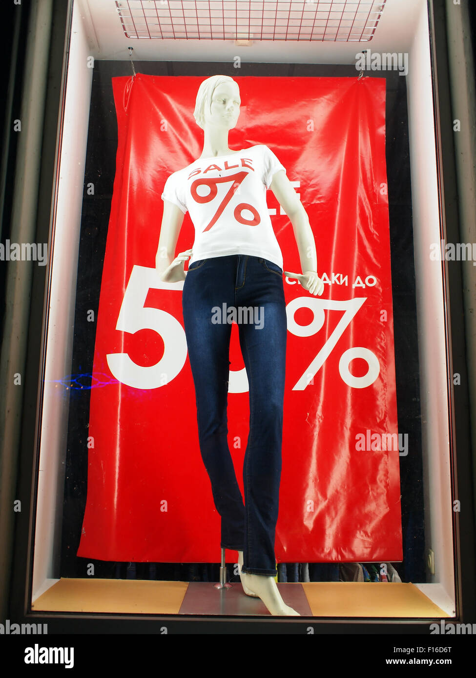 Weibliche Schaufensterpuppe in das Fenster hinter dem Glas, gekleidet in Jeans und einem weißen T-shirt. Inschriften in Russisch und Englisch - Sal Stockfoto