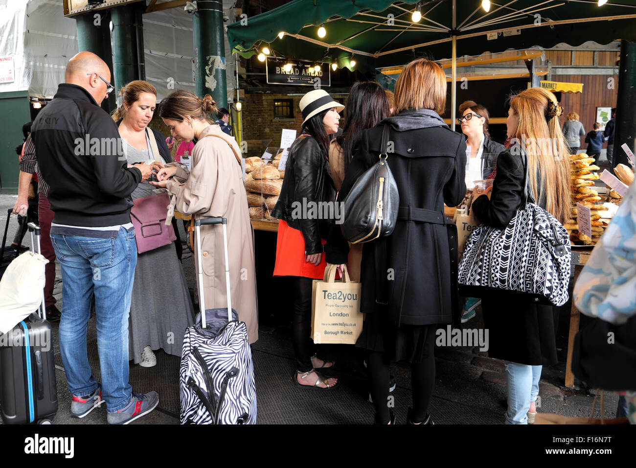 Touristen mit Gepäck stehen an der Straße Imbissbuden in Borough Market London UK KATHY DEWITT Stockfoto