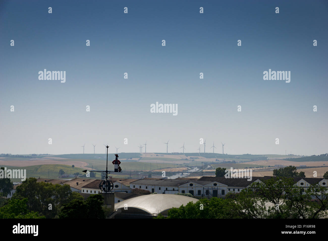 Windkraftanlagen am fernen Horizont von Jerez De La Frontera, Spanien, mit Tio Pepe gebrandmarkt Windfahne. Stockfoto