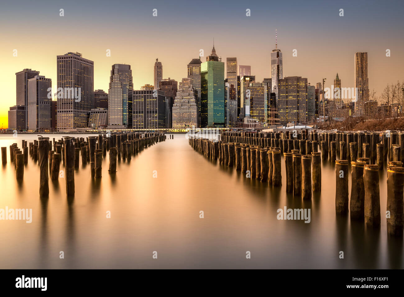 Langzeitbelichtung der Lower Manhattan Skyline bei Sonnenuntergang mit einem alten Brooklyn Pier im Vordergrund Stockfoto