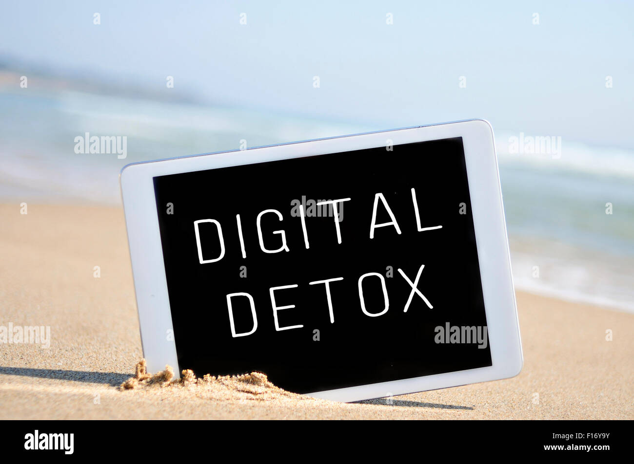 ein Tablet-Computer mit der Text digital Detox geschrieben in seinem Bildschirm platziert in den Sand des Strandes Stockfoto