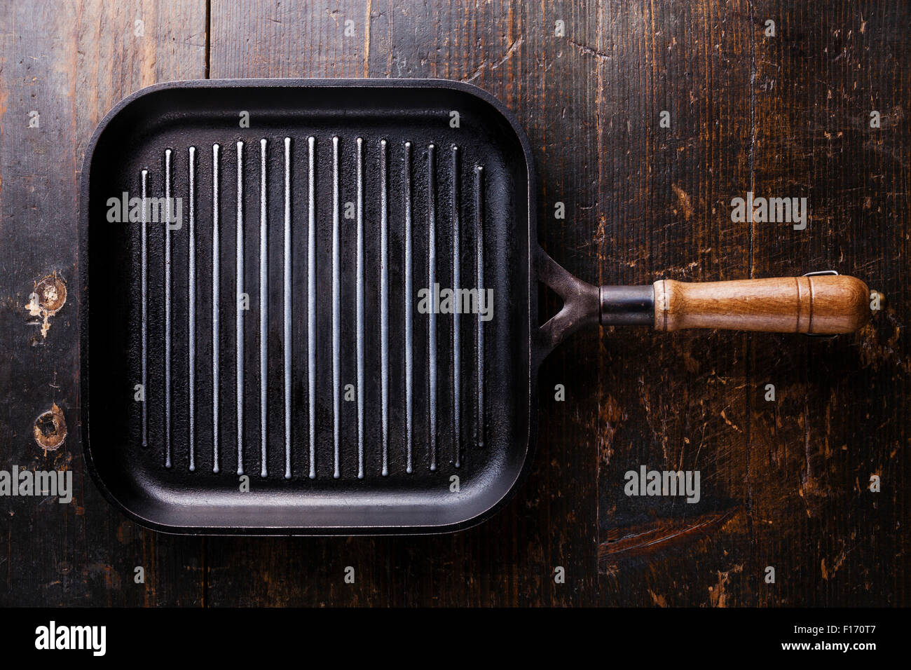 Schwarzes Eisen leeren Grillpfanne auf alte dunkle braune hölzerne Struktur Hintergrund Stockfoto