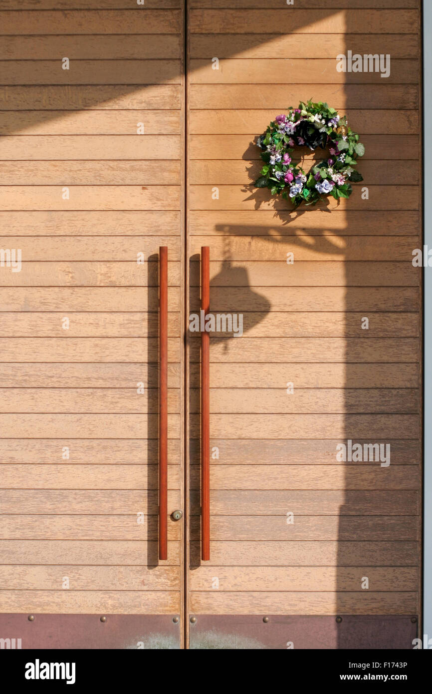 Haustür aus Holz klare Linien Glocke Silhouette und Blumenkranz Stockfoto