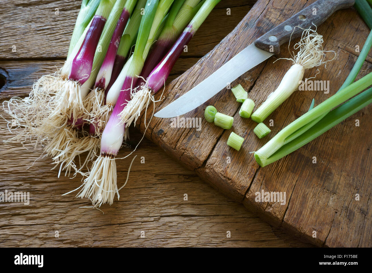 Frischen roten Zwiebeln und einem Küchenmesser auf einem alten Holzbrett Stockfoto