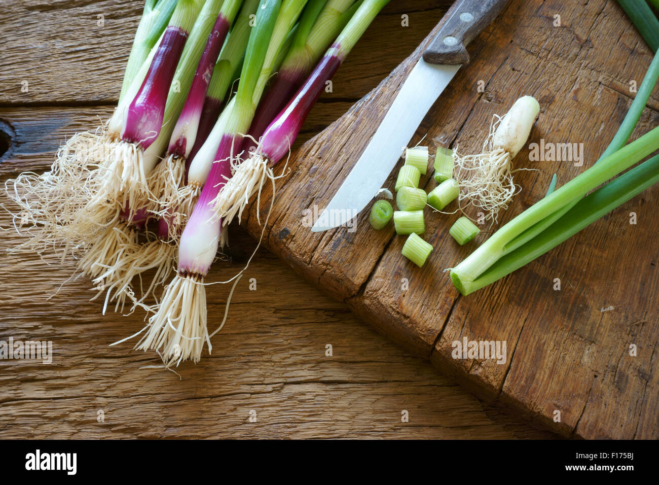 Frischen roten Zwiebeln und einem Küchenmesser auf einem alten Holzbrett Stockfoto