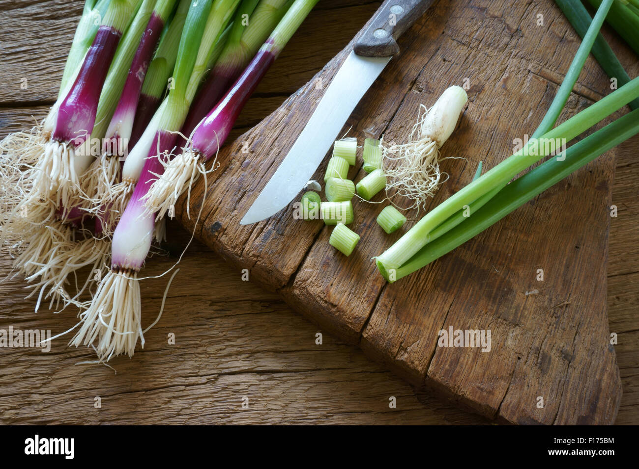 Frischen roten Zwiebeln und einem Küchenmesser auf einem alten Holzbrett Stockfoto