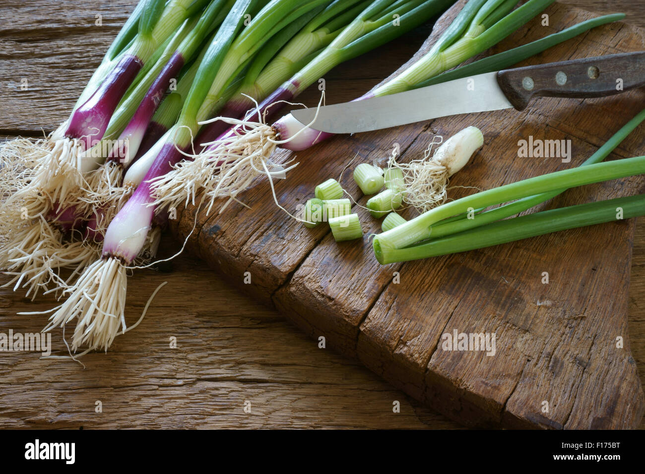 Frischen roten Zwiebeln und einem Küchenmesser auf einem alten Holzbrett Stockfoto