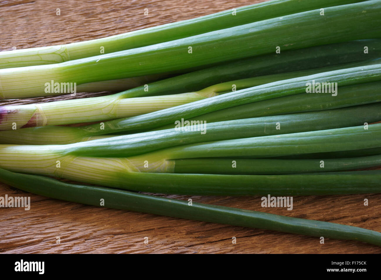Bund frischen grünen Frühlingszwiebeln auf rustikalem Holzbrett Stockfoto