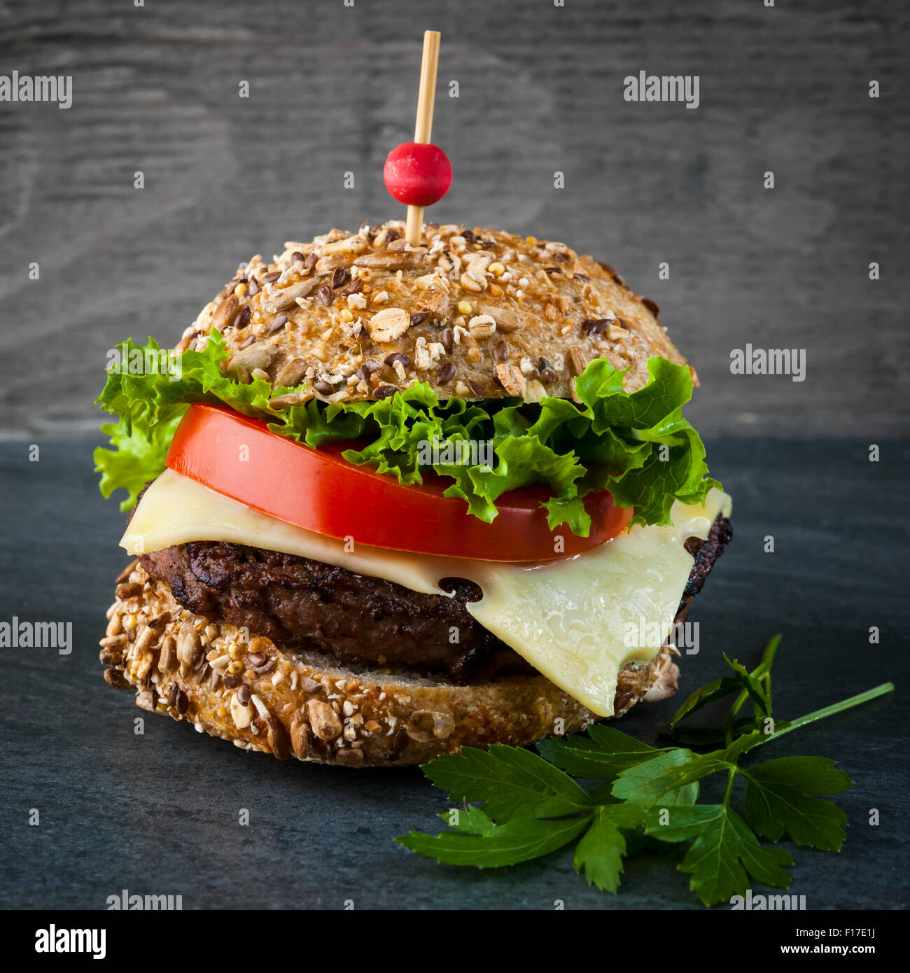 Gourmet-Hamburger mit Käse und frischem Gemüse auf Mehrkorn Brötchen auf dunklem Hintergrund, quadratischen format Stockfoto