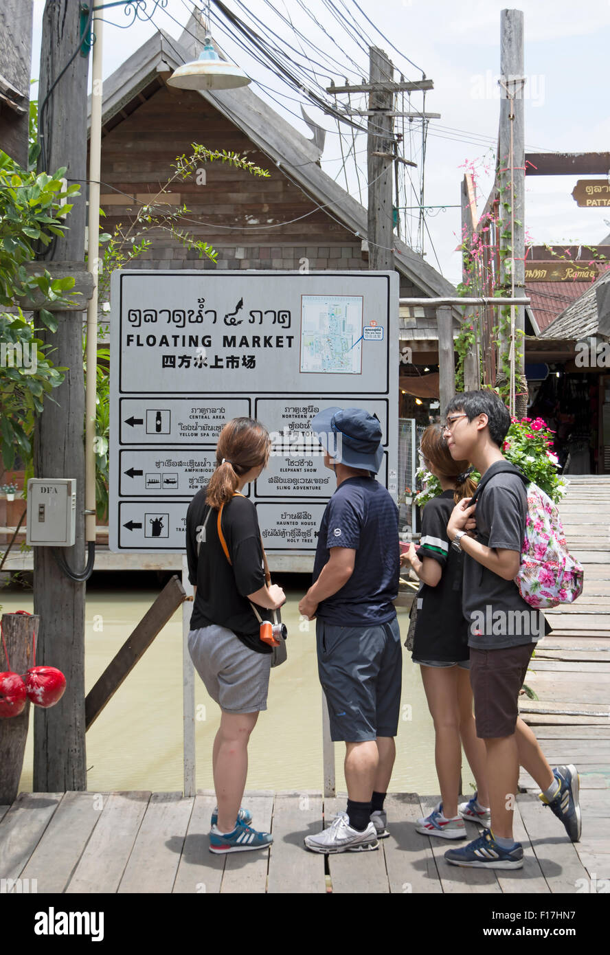 asiatische Touristen ein mehrsprachiges Schild auf dem schwimmenden Markt, eine touristische Attraktion in Pattaya, Thailand, Südostasien Stockfoto