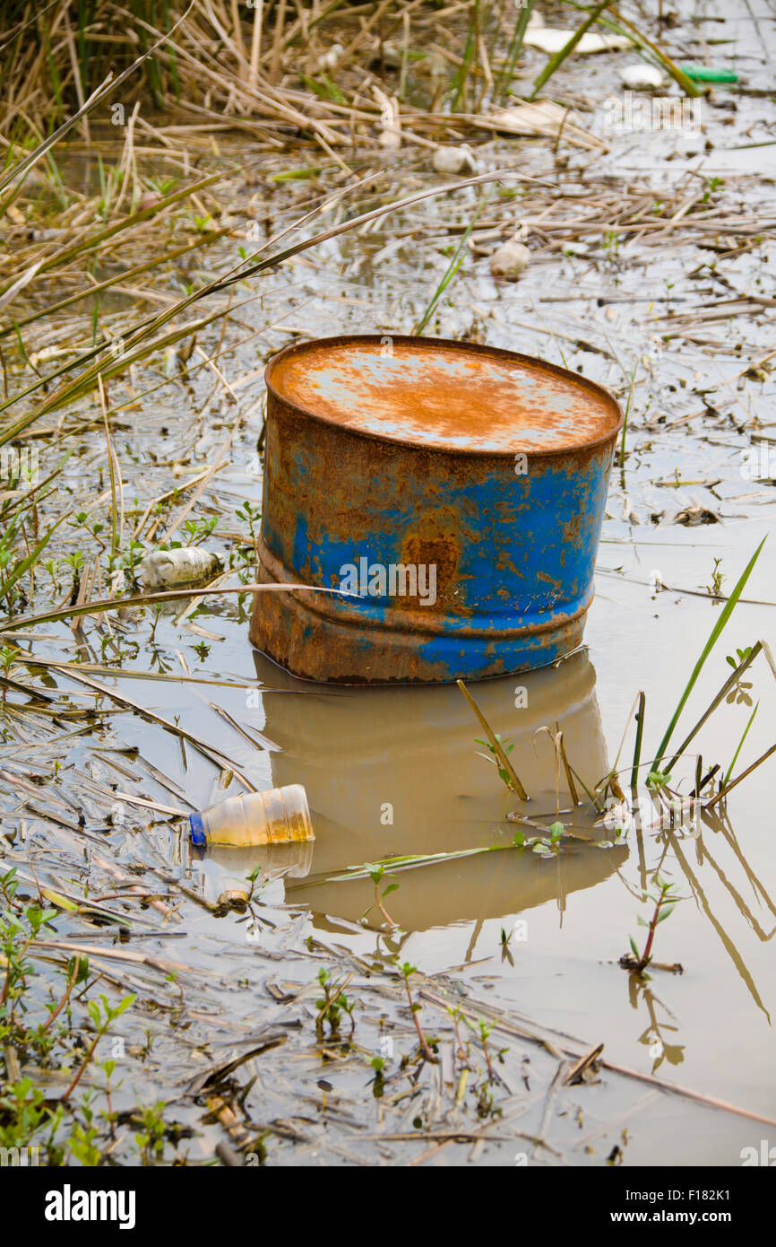 Müll und Giftmüll sitzen in einem Teich von braunem Wasser Stockfoto