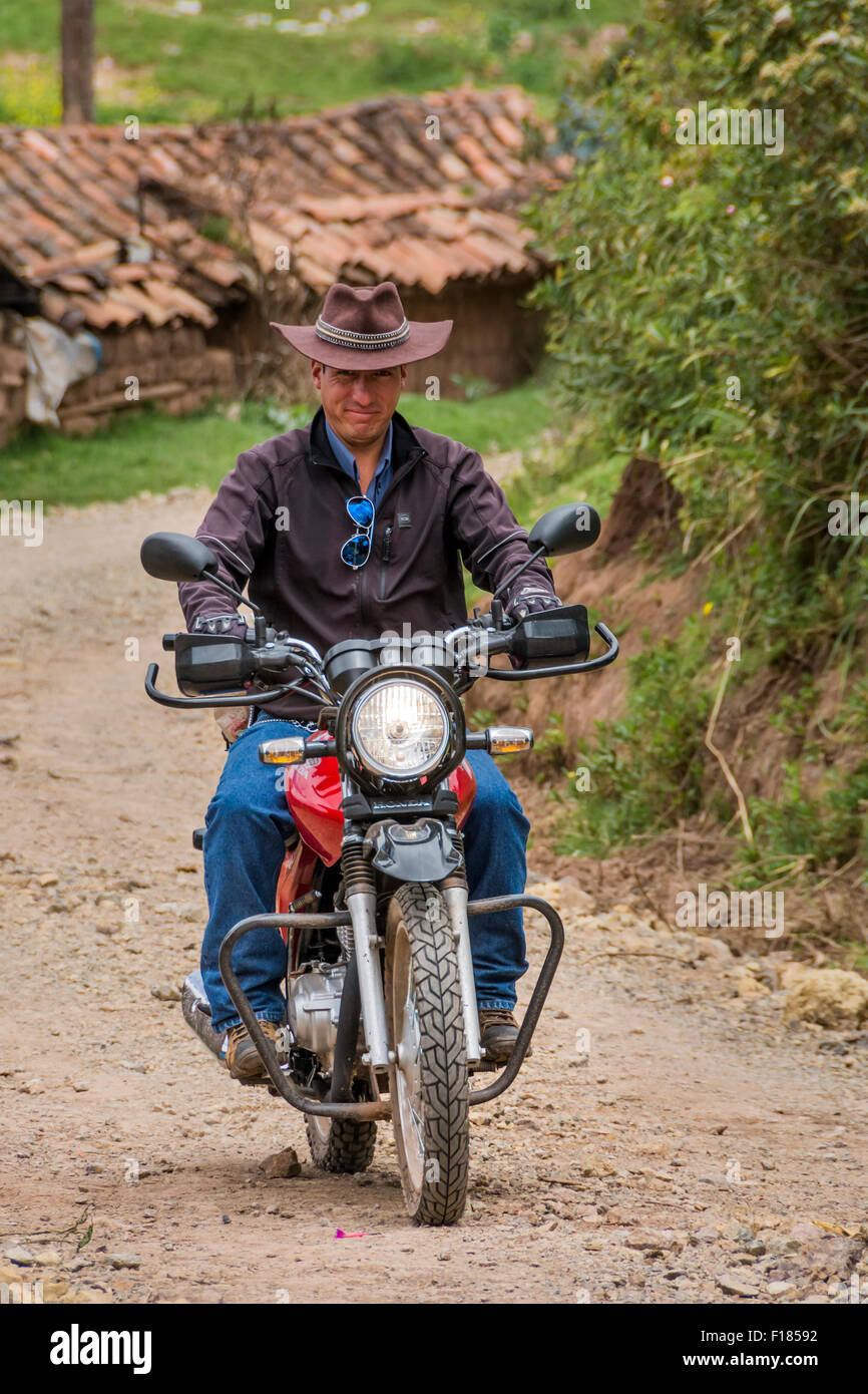 Mann reitet Motorcyle durch Dorf Misminay; Heiliges Tal, Urubamba Provinz, Peru. Stockfoto