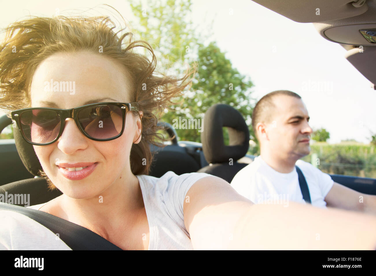 Frau genießt die Fahrt im Auto Cabrio bei Sonnenuntergang Stockfoto