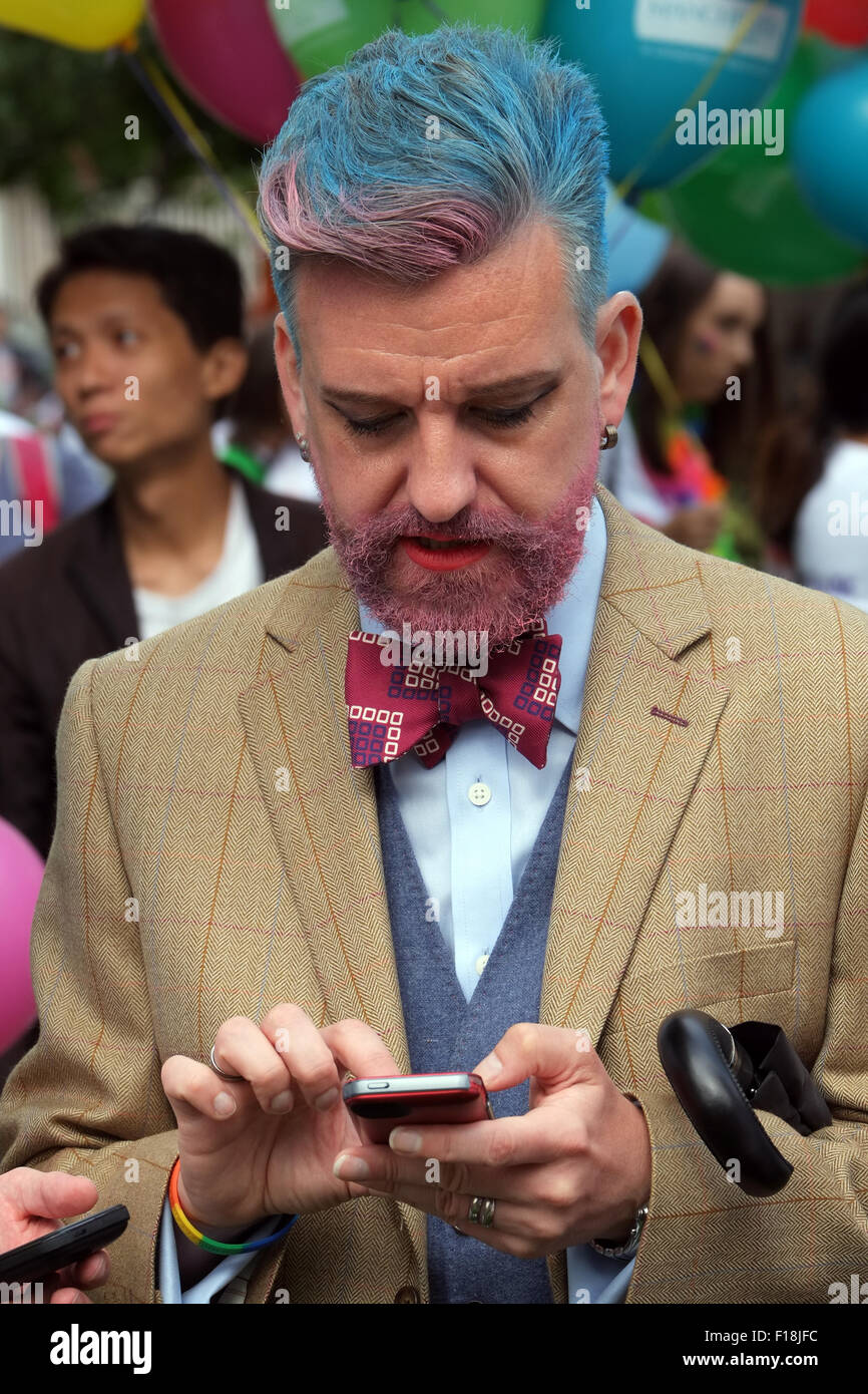 Homosexuell Mann mit seinem Smartphone während der Vorbereitung für die Manchester Pride 2015 große Parade durch die Innenstadt Stockfoto