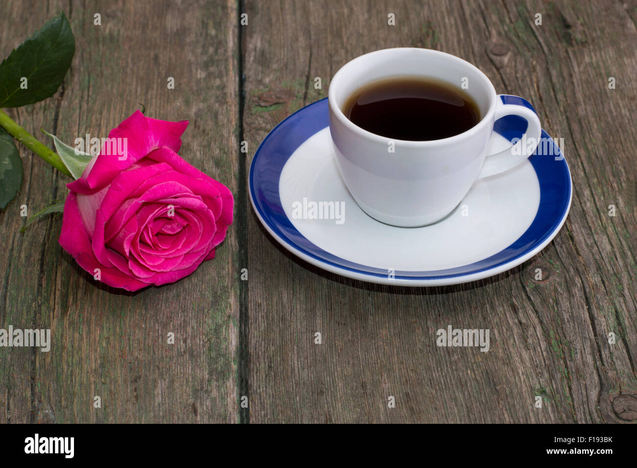 Tasse Kaffee und einsame rote Rose auf dem Tisch Stockfoto