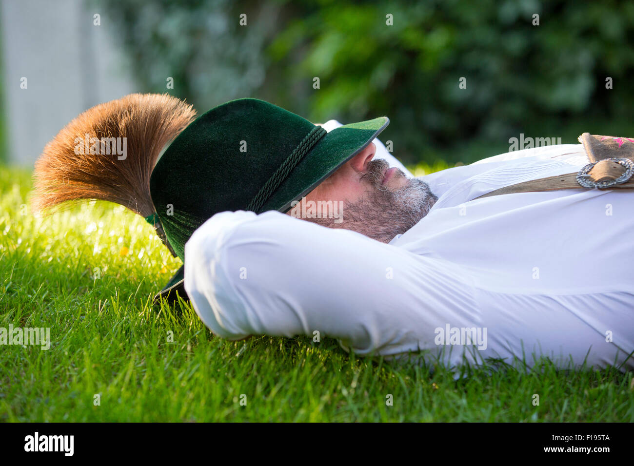 Mann in bayerischer Tracht schlafen draußen auf der Wiese Stockfoto