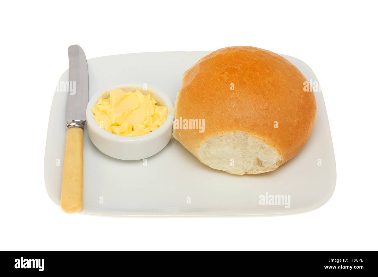 Brötchen mit Butter und ein Messer auf einem Teller isoliert gegen weiß Stockfoto