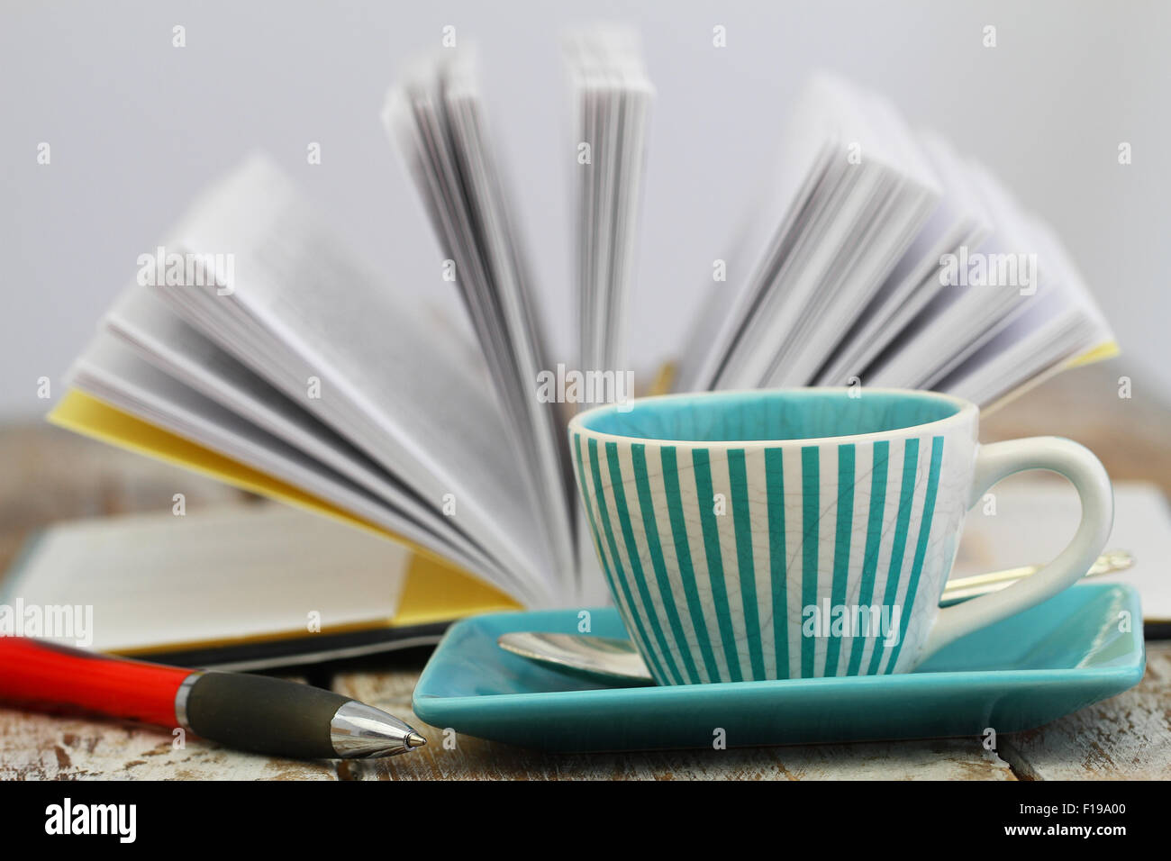 Tasse Kaffee mit offenen Buch im Hintergrund Stockfoto