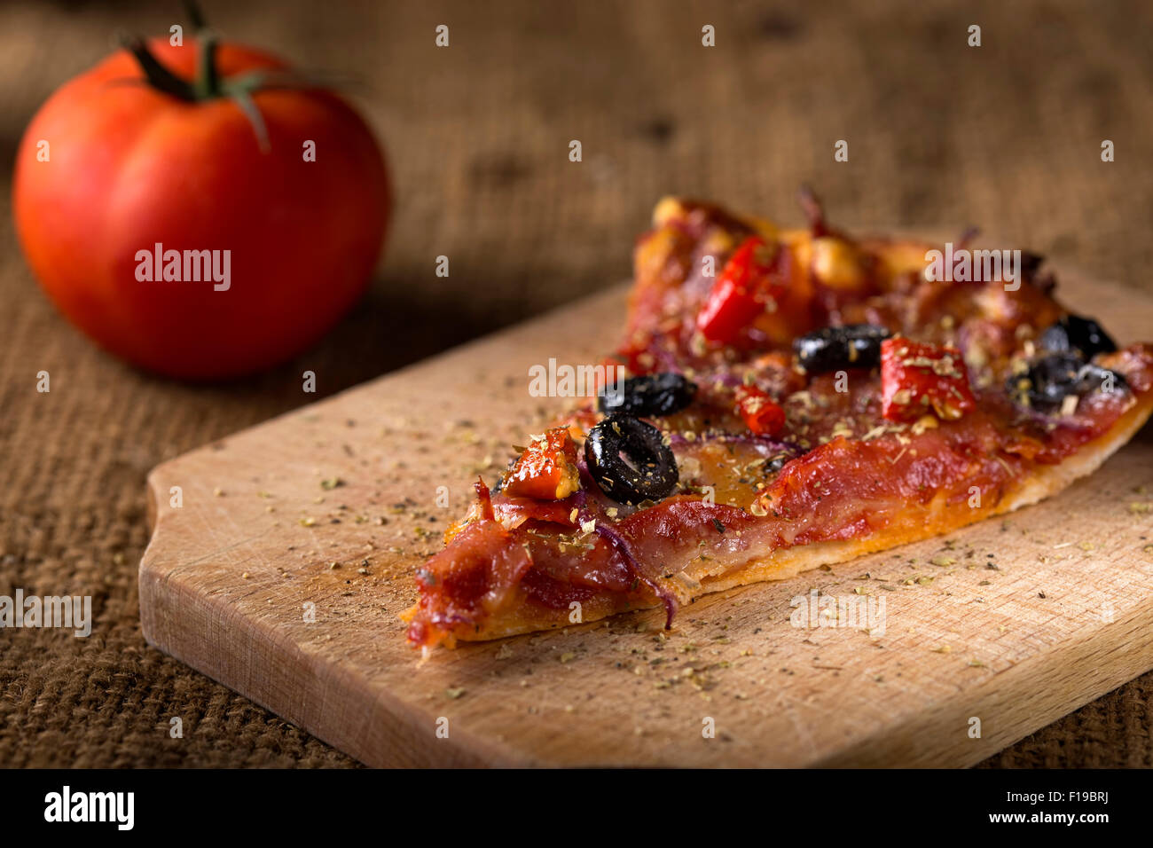 Ein Stück Diavola Pizza auf Holz mit Tomate Stockfoto