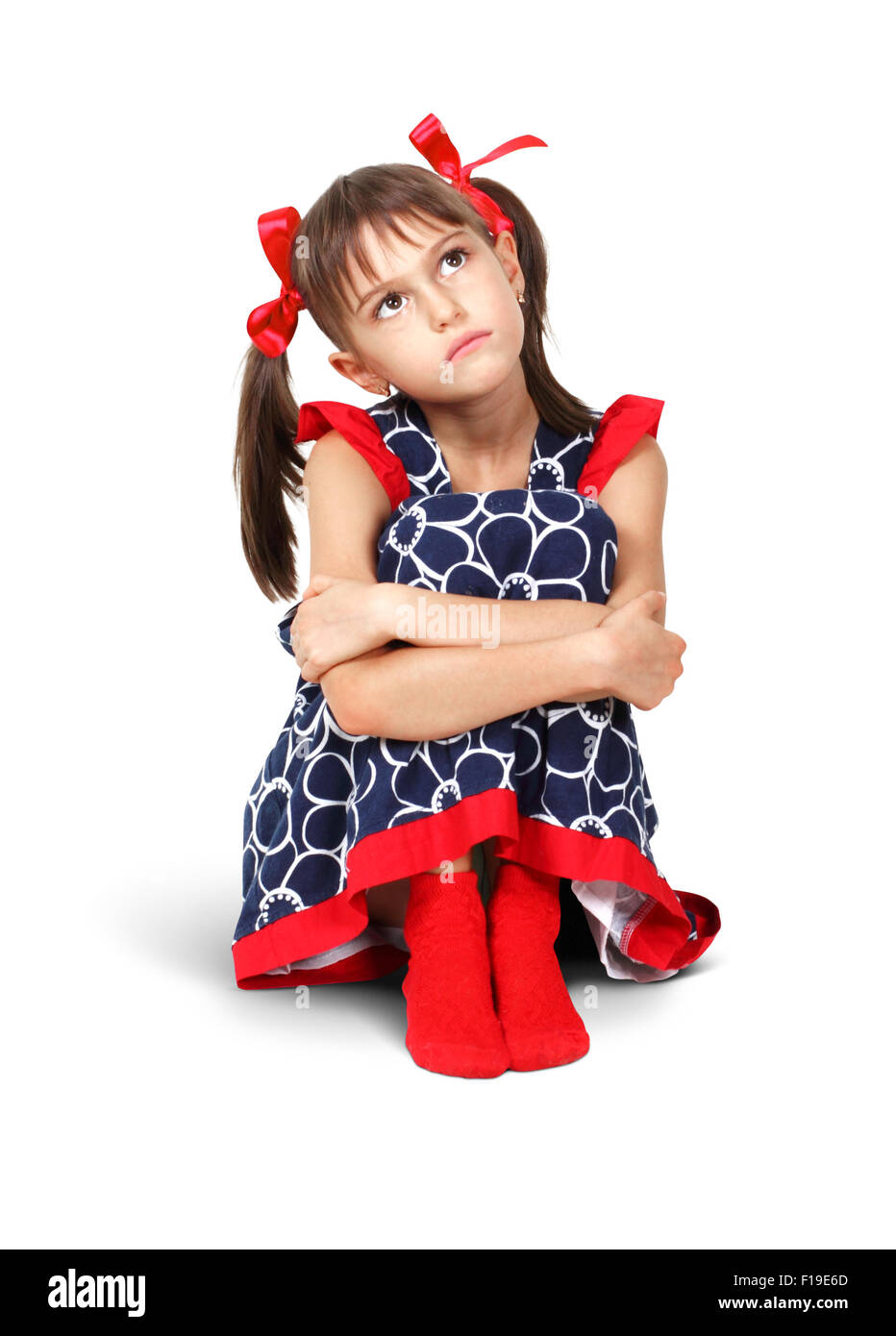 Sitzt traurig, nachdenklich Kind Mädchen mit roten Schleifen auf weiß Stockfoto