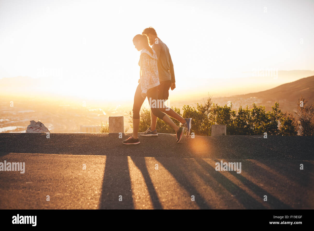 Paar Fuß entlang der Straße bei Sonnenaufgang. Paar einen Spaziergang am Hang Road mit hellem Sonnenlicht zu sprechen. Stockfoto