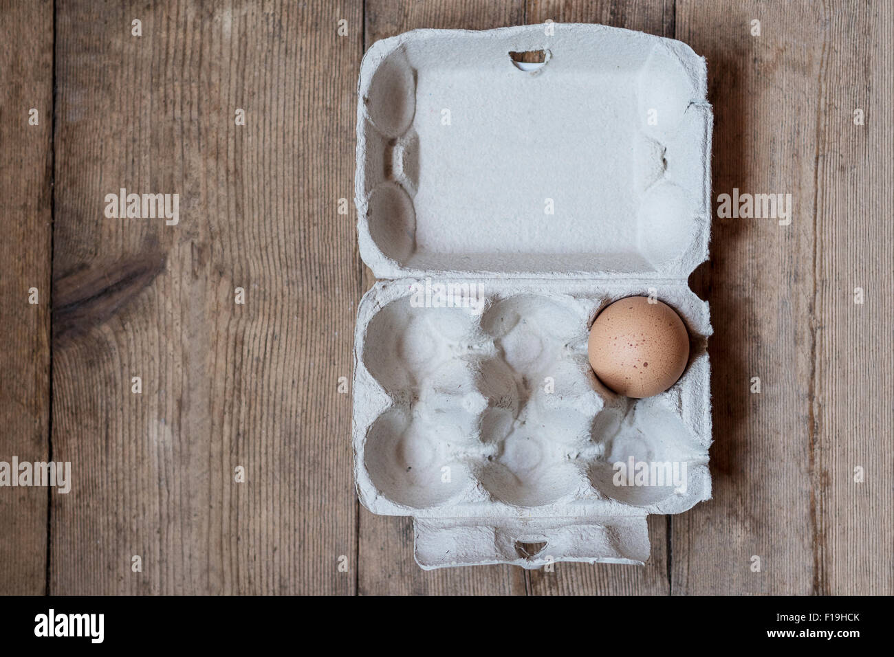 Ein Ei in einem Karton auf einem alten Holztisch Stockfoto