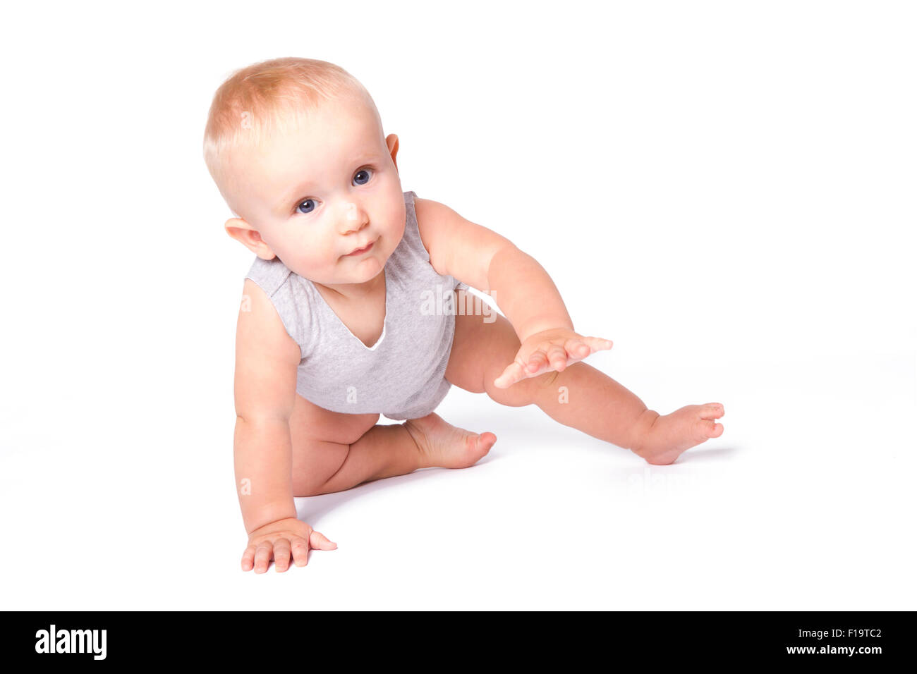 Studioaufnahme von Baby Boy Spielen auf dem Boden in die Kamera schaut. Stockfoto
