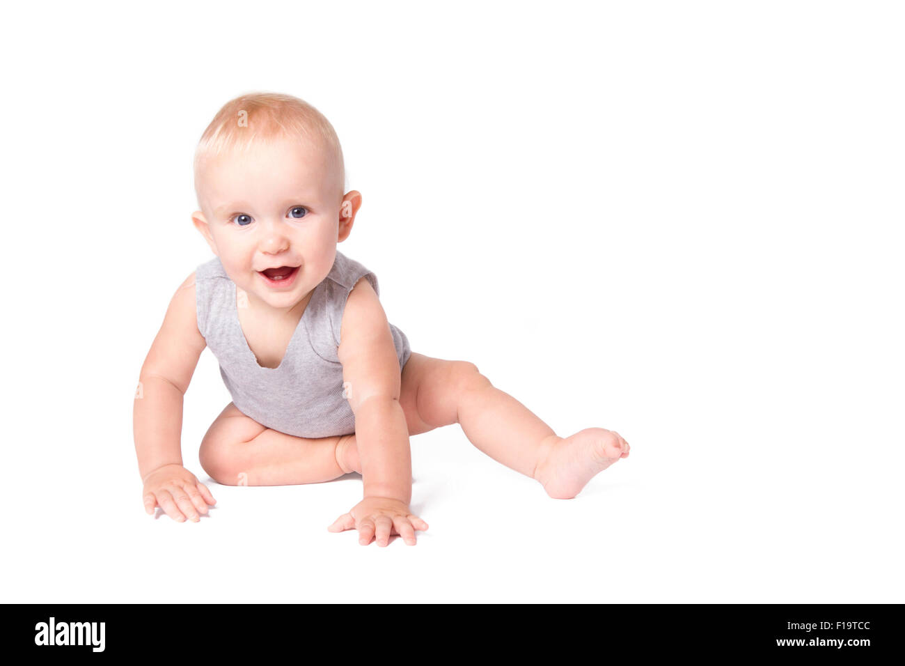 Studioaufnahme von Baby Boy Spielen auf dem Boden in die Kamera schaut. Stockfoto