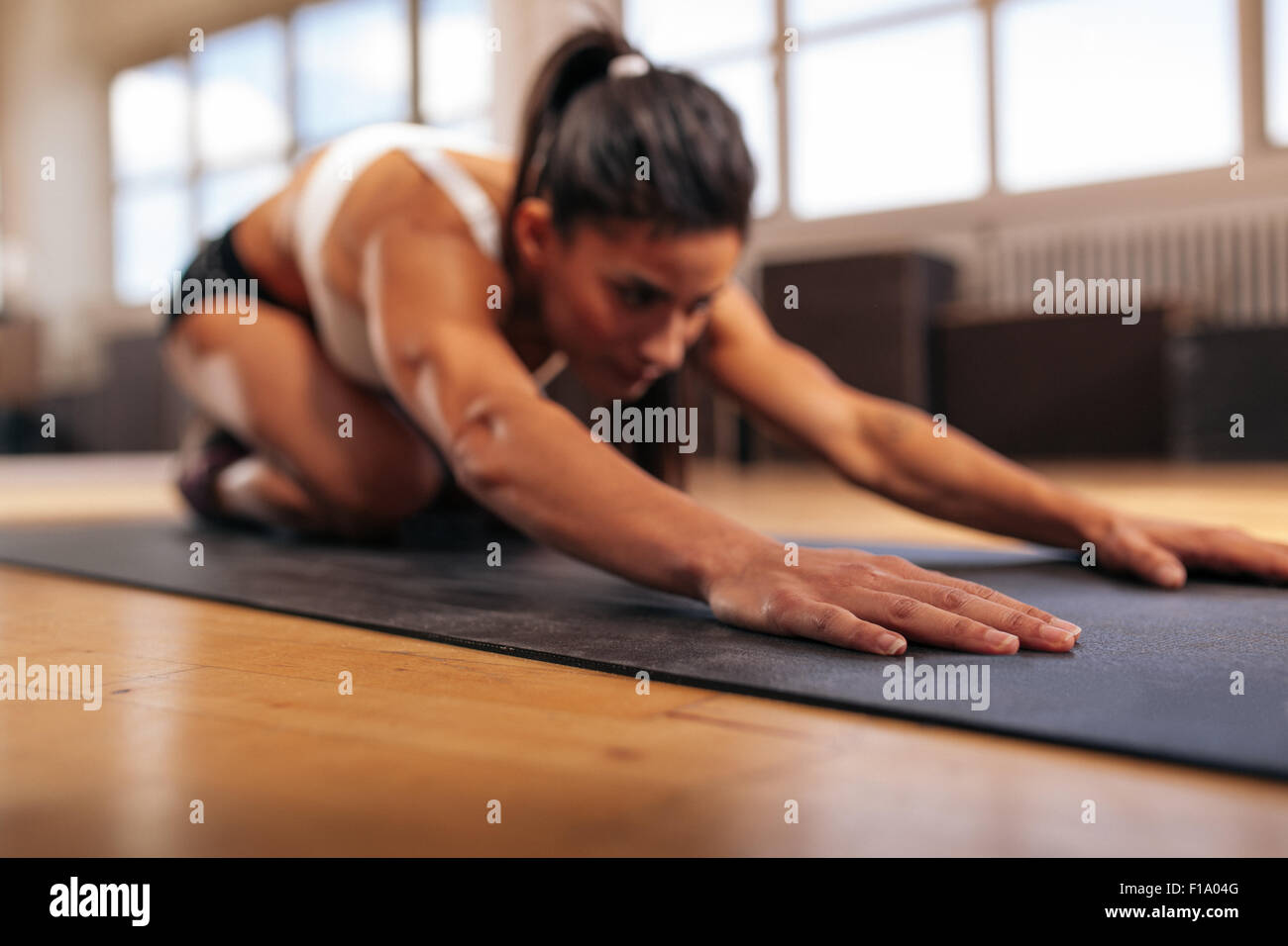 Frau tut stretching Workout auf Fitness-Matte, Fokus auf Händen, Fitness weiblich Yoga auf Gymnastikmatte in Turnhalle durchführen. Stockfoto