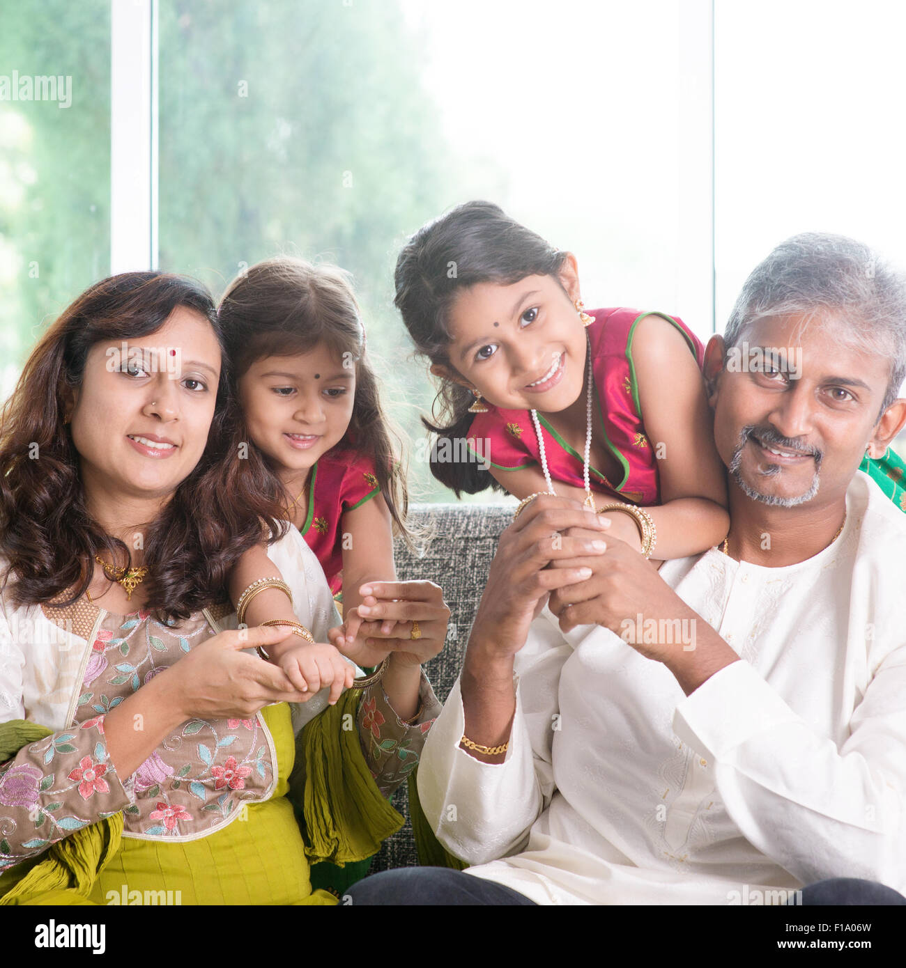 Glückliche indische Familie zu Hause. Asiatischen Eltern mit ihren Kindern auf dem Sofa sitzen. Eltern und Kinder indoor Lifestyle. Stockfoto