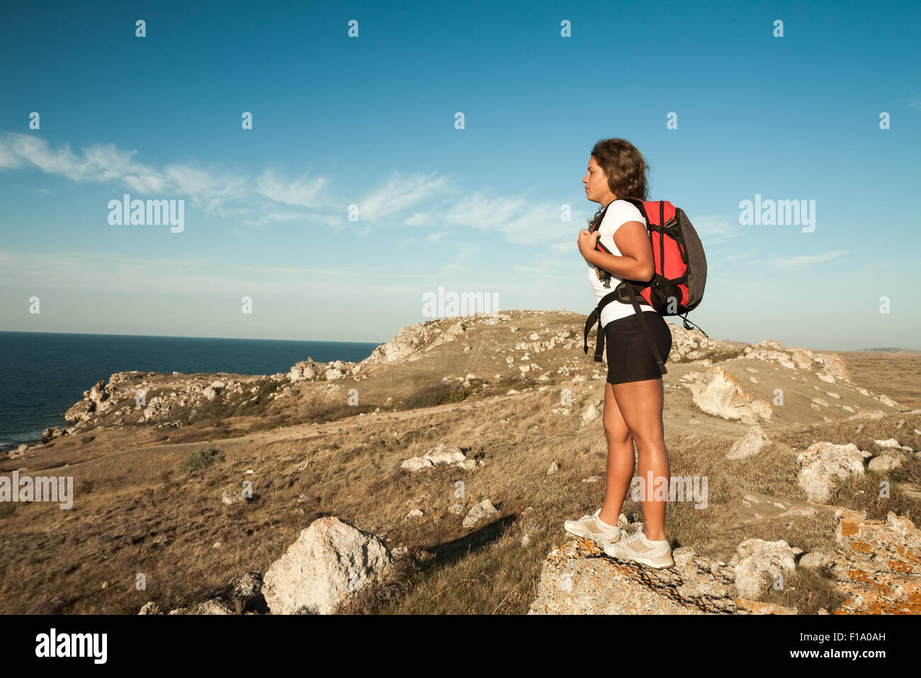 Frau Wanderer mit Rucksack steht auf Berg Küstenfels Stockfoto