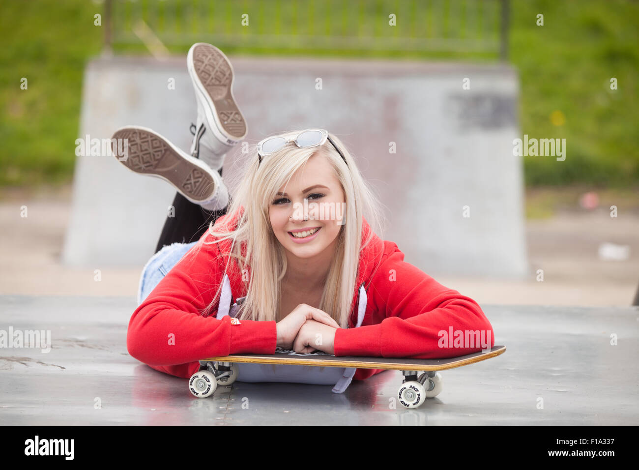 Ziemlich junges Mädchen hinlegen auf den Bauch außerhalb in einem Skatepark. Stockfoto