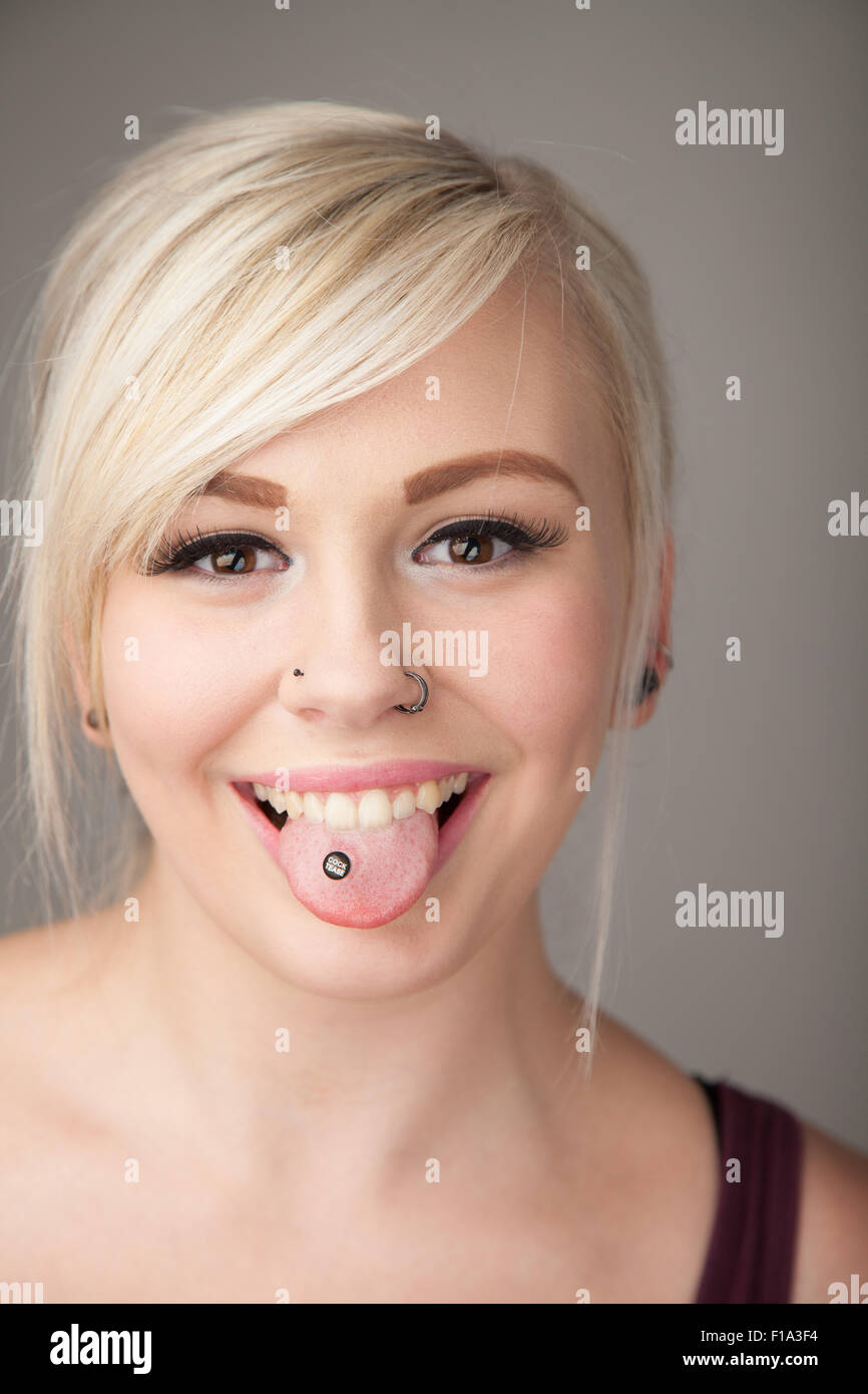 Niedlich aussehende Teenager-Mädchen mit ihrer gepiercten Zunge heraus. Stockfoto
