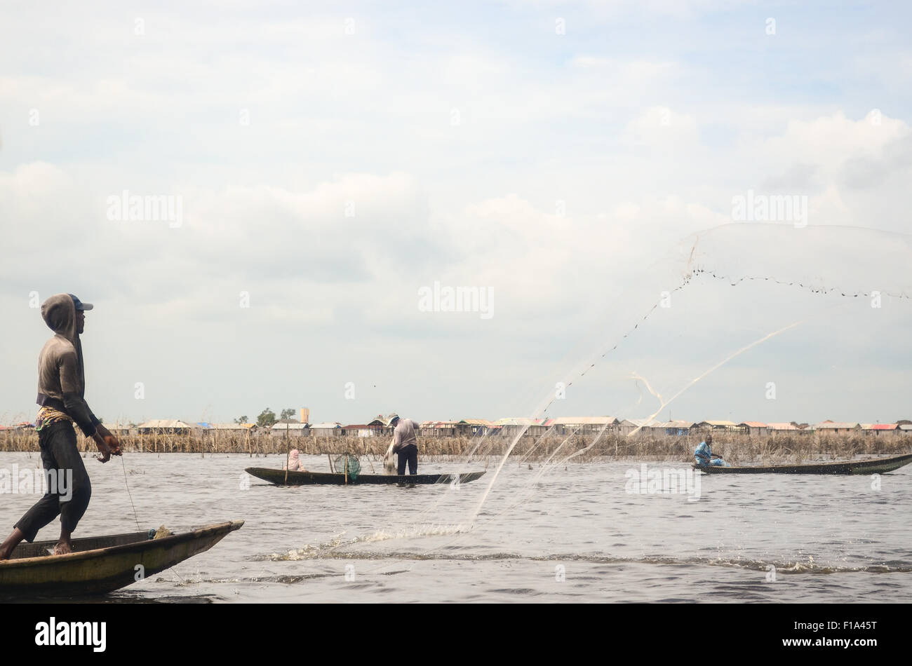 Fischer werfen ein Fischernetz in Ganvié, das "Venedig von Afrika", Dorf der Pfahlbauten an einem See in der Nähe von Cotonou in Benin Stockfoto