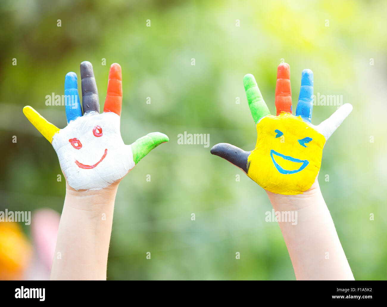 Farbige Hände mit Lächeln in bunten Farben vor grünen Sommer Hintergrund gemalt. Lifestyle-Konzept Stockfoto