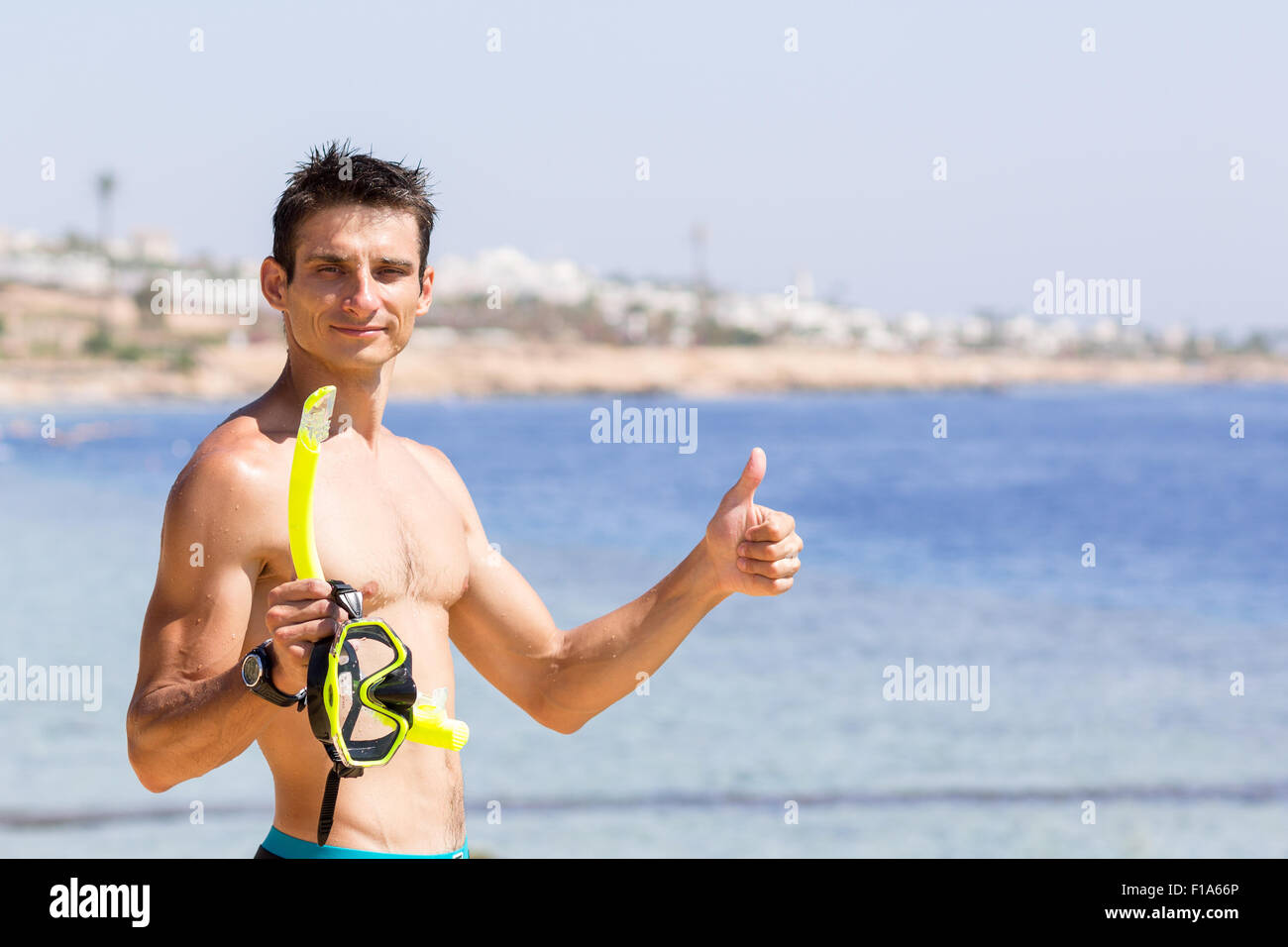 Junger lächelnder Mann hält Schnorchelausrüstung und Daumen auftaucht. Sommer Urlaub Hintergrund mit textfreiraum rechts Stockfoto