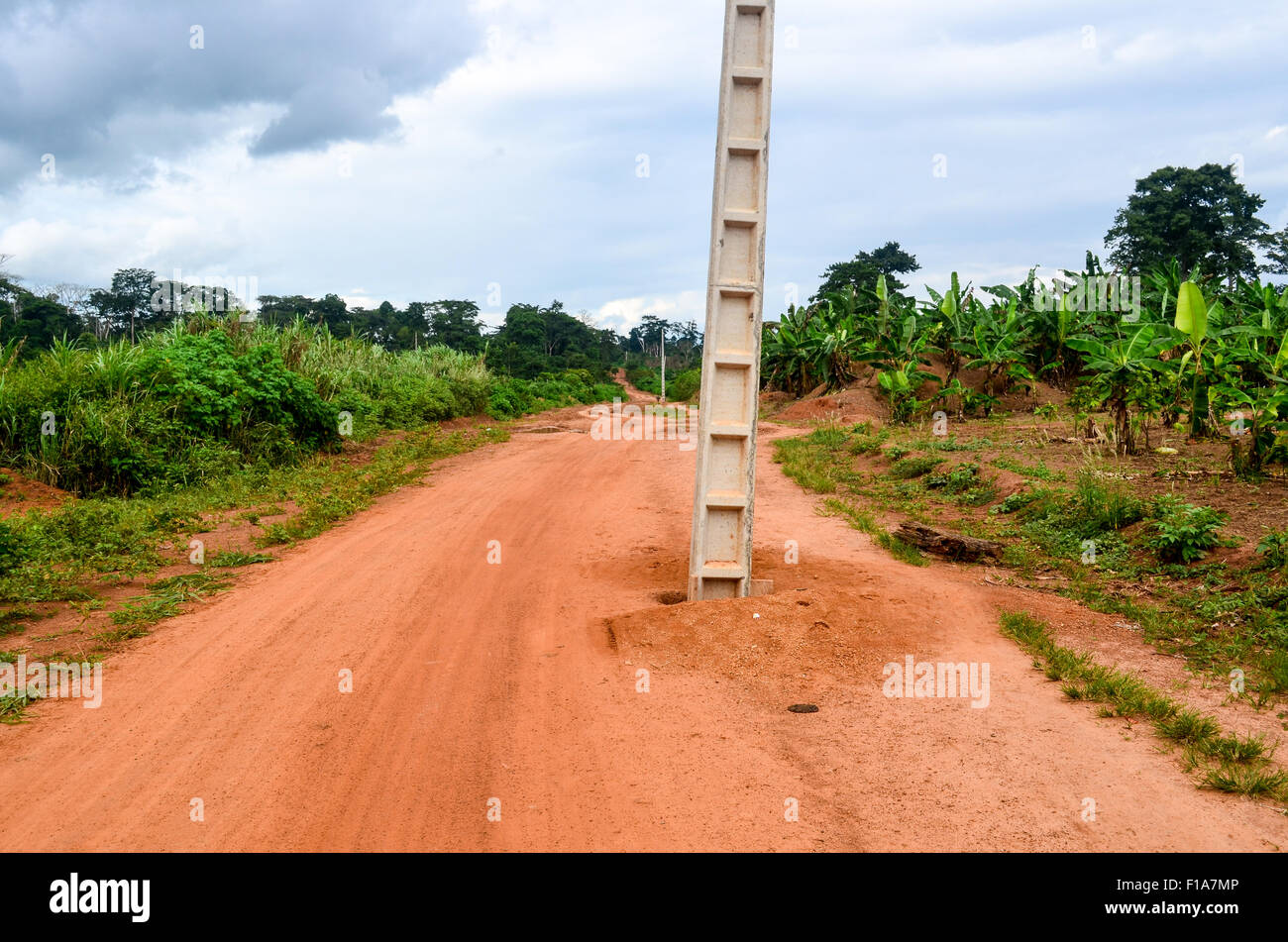 Elektrische Pol in der Mitte eine rote Erde unbefestigte Straße in ländlichen Regionen Afrikas Stockfoto