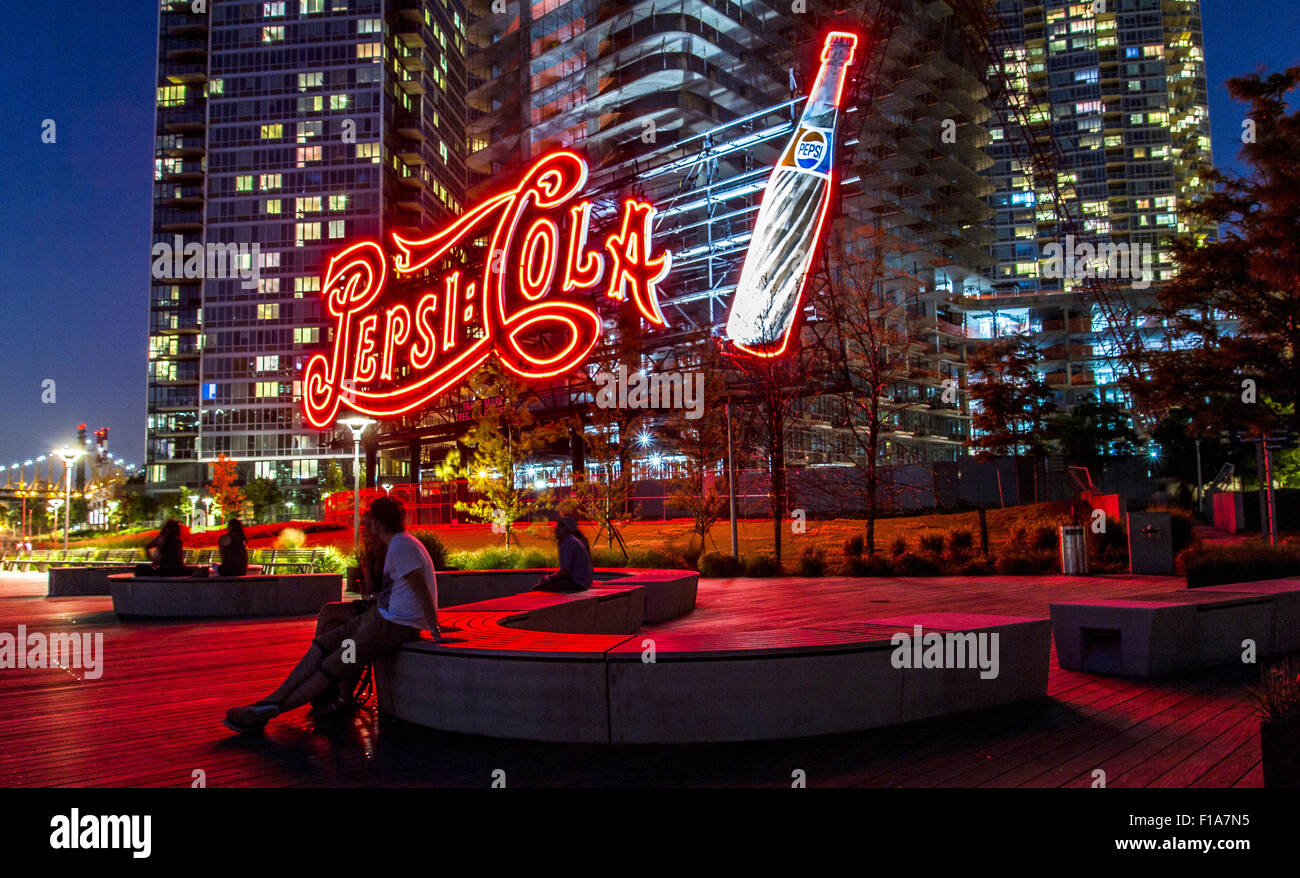 Paar in rotes Licht aus dem riesigen neon Pepsi Cola Schild gebadet, Gantry Plaza State Park, Long Island City NY Stockfoto
