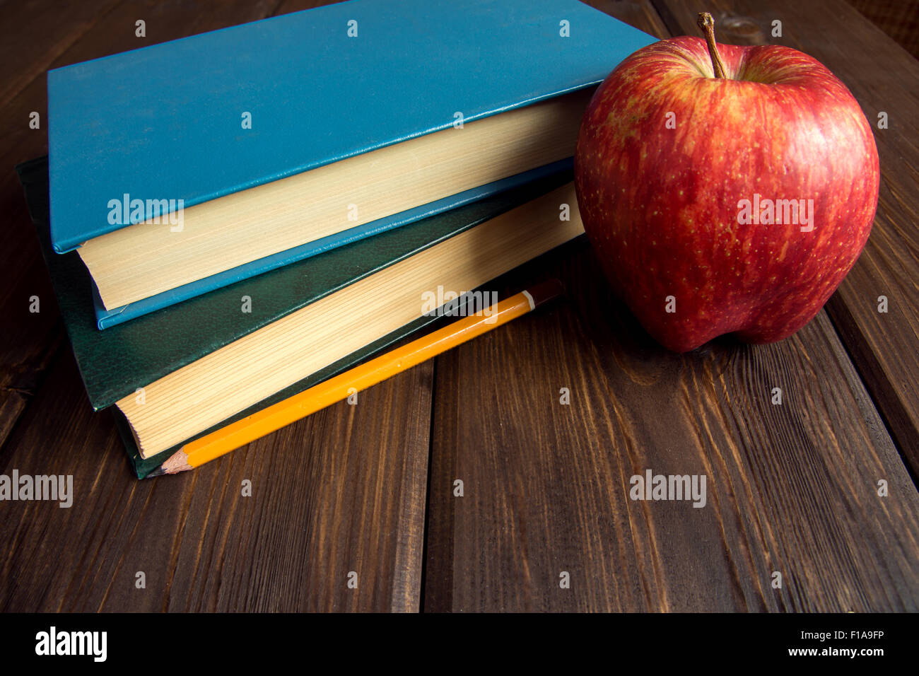 Alte Bücher und roter Apfel auf hölzernen Hintergrund mit Textfreiraum Stockfoto