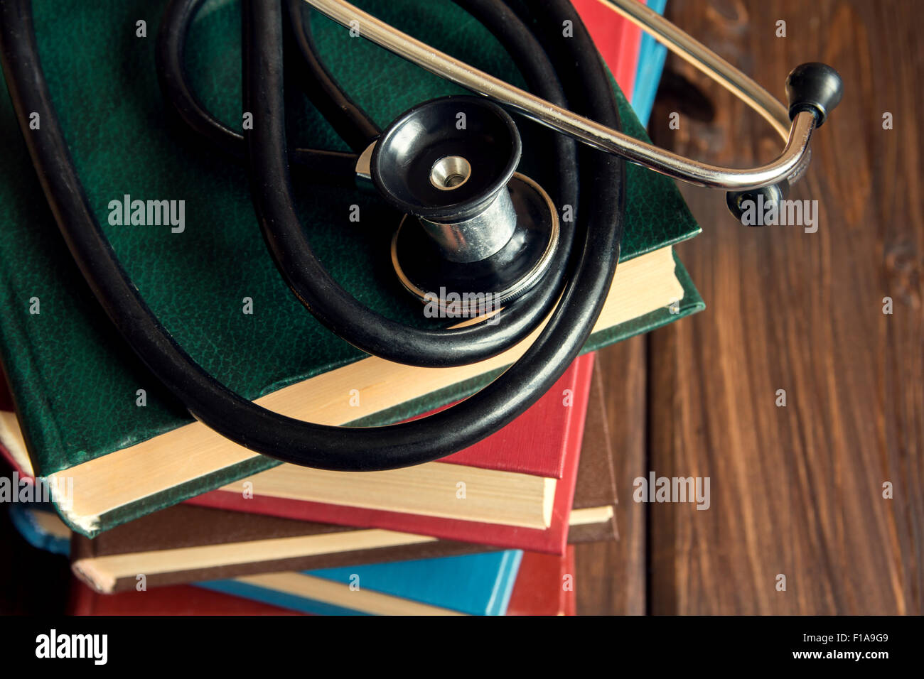 Stethoskop und alte Bücher über Holztisch mit Textfreiraum, medizinische Ausbildungskonzept Stockfoto