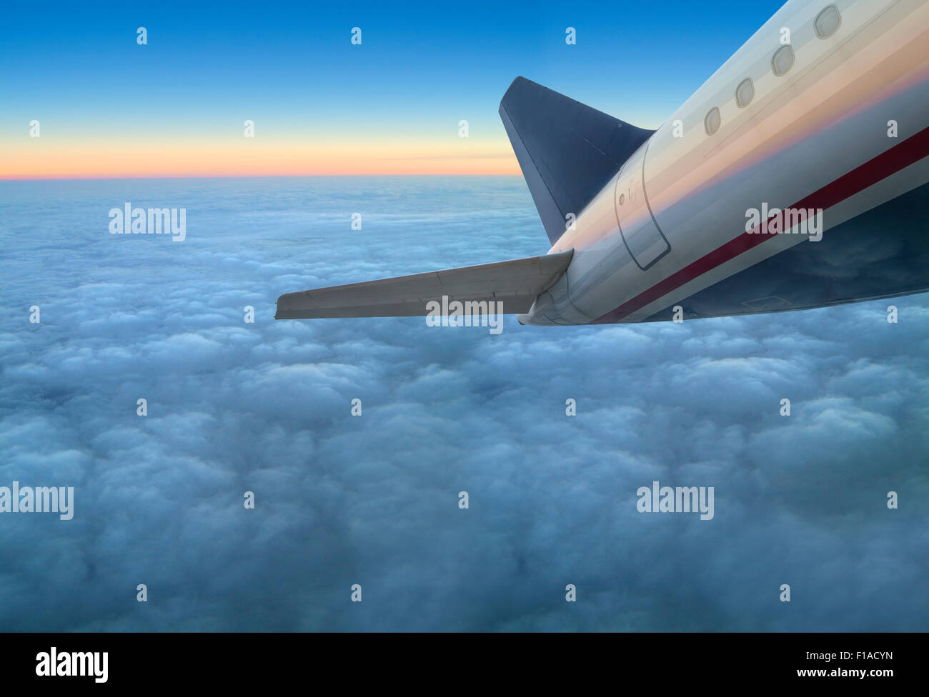 Erste kommerzielle Fluggesellschaft Jet Flugzeug fliegen über Wolken bei Sonnenuntergang Stockfoto