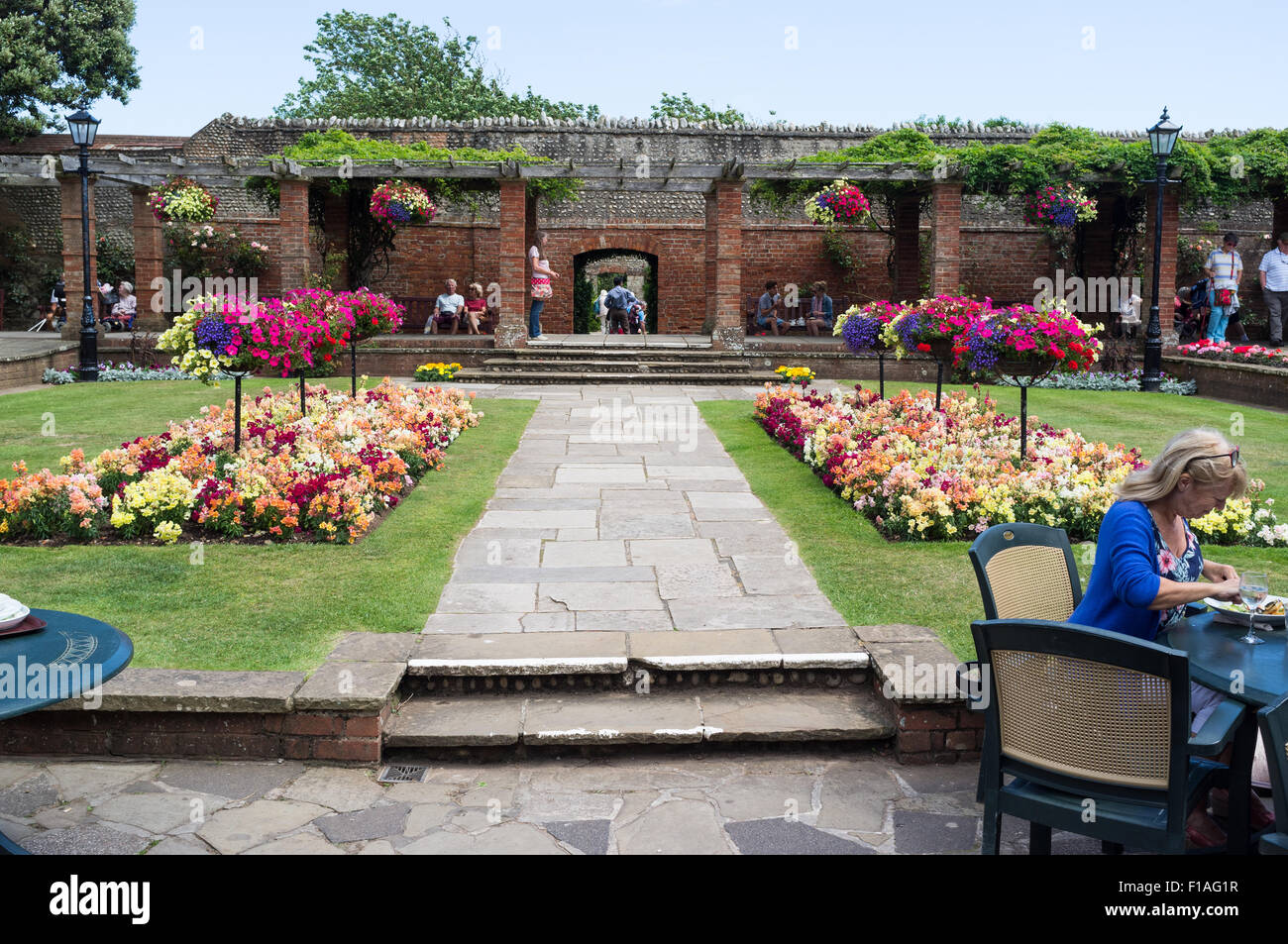 Sidmouth 2015. Connaught Gärten im Sidmouth. Blumen in voller Blüte und mit Menschen sitzen mit etwas zu essen Essen im Vordergrund. Stockfoto