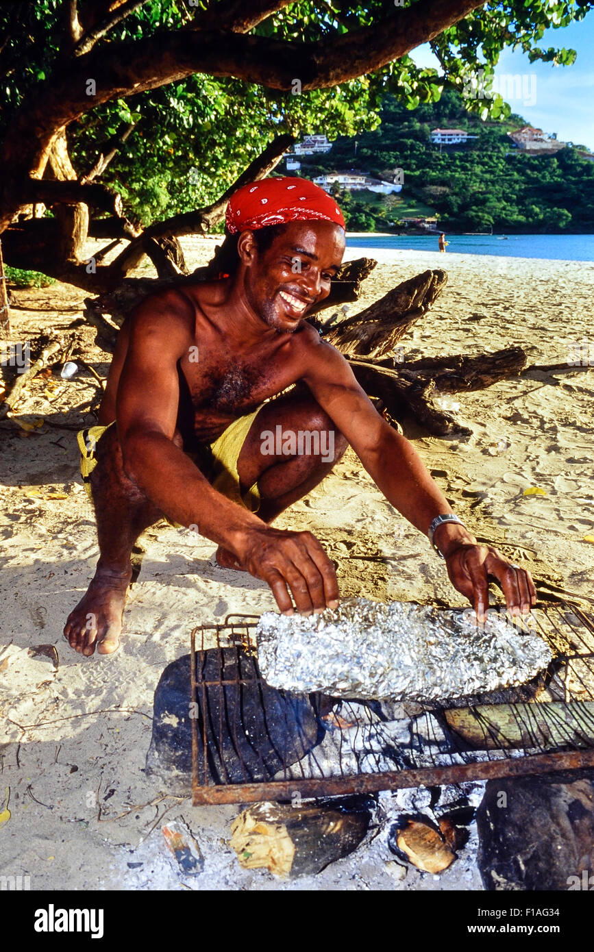 Grenadian Mann Kochen sein Abendmahl am Morne Rouge Strand Angeln. Grenada. Stockfoto