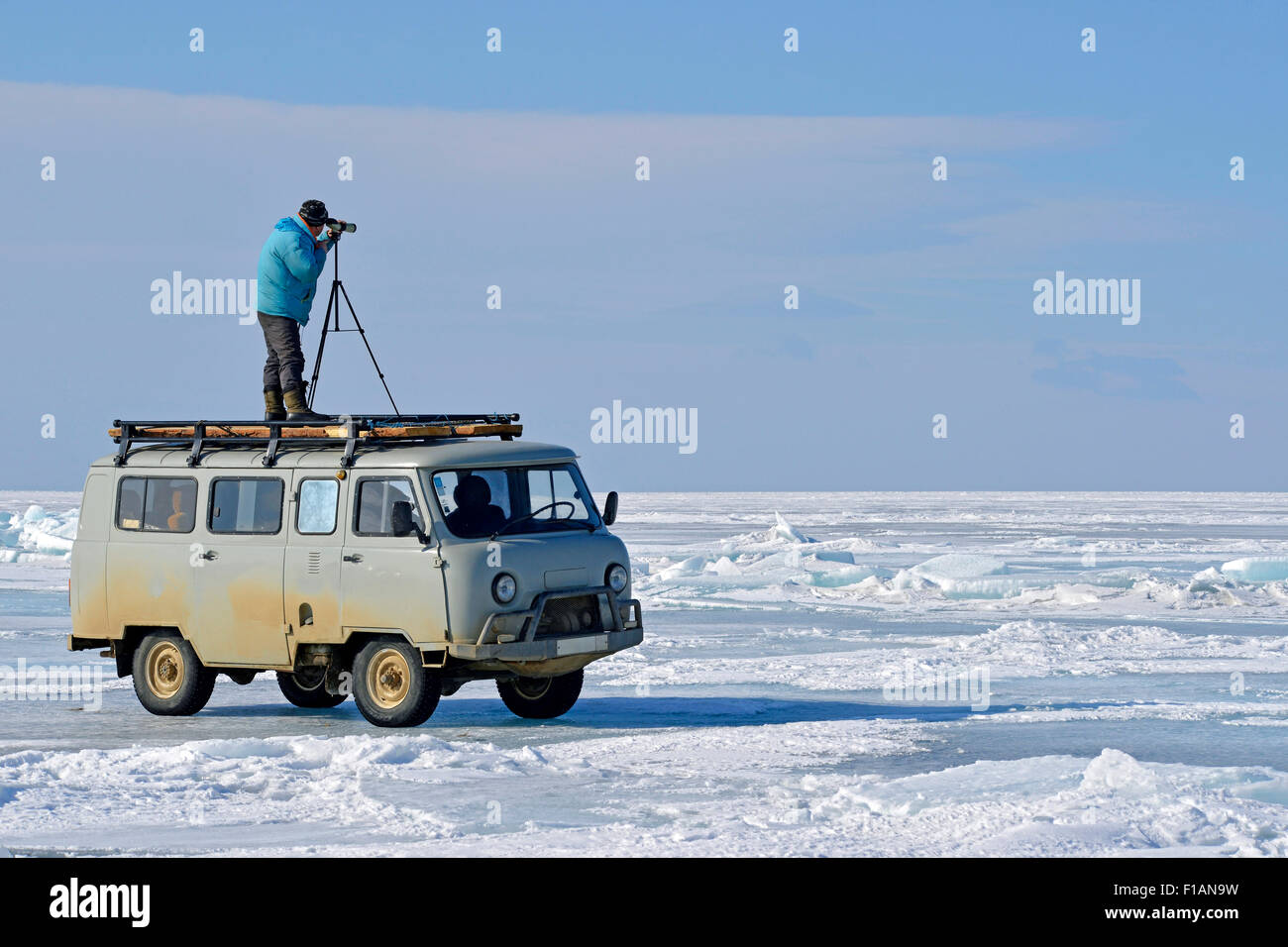 Mann Russlands, dem Baikalsee, Teleskop steht auf Kleinbus auf zugefrorenen See auf der Suche nach Dichtungen Stockfoto