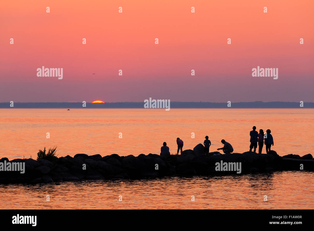 Menschen, die Silhouette gegen einen lebendigen Himmel Sonnenuntergang über Lake Simcoe. Willow Beach, Ontario, Kanada. Stockfoto