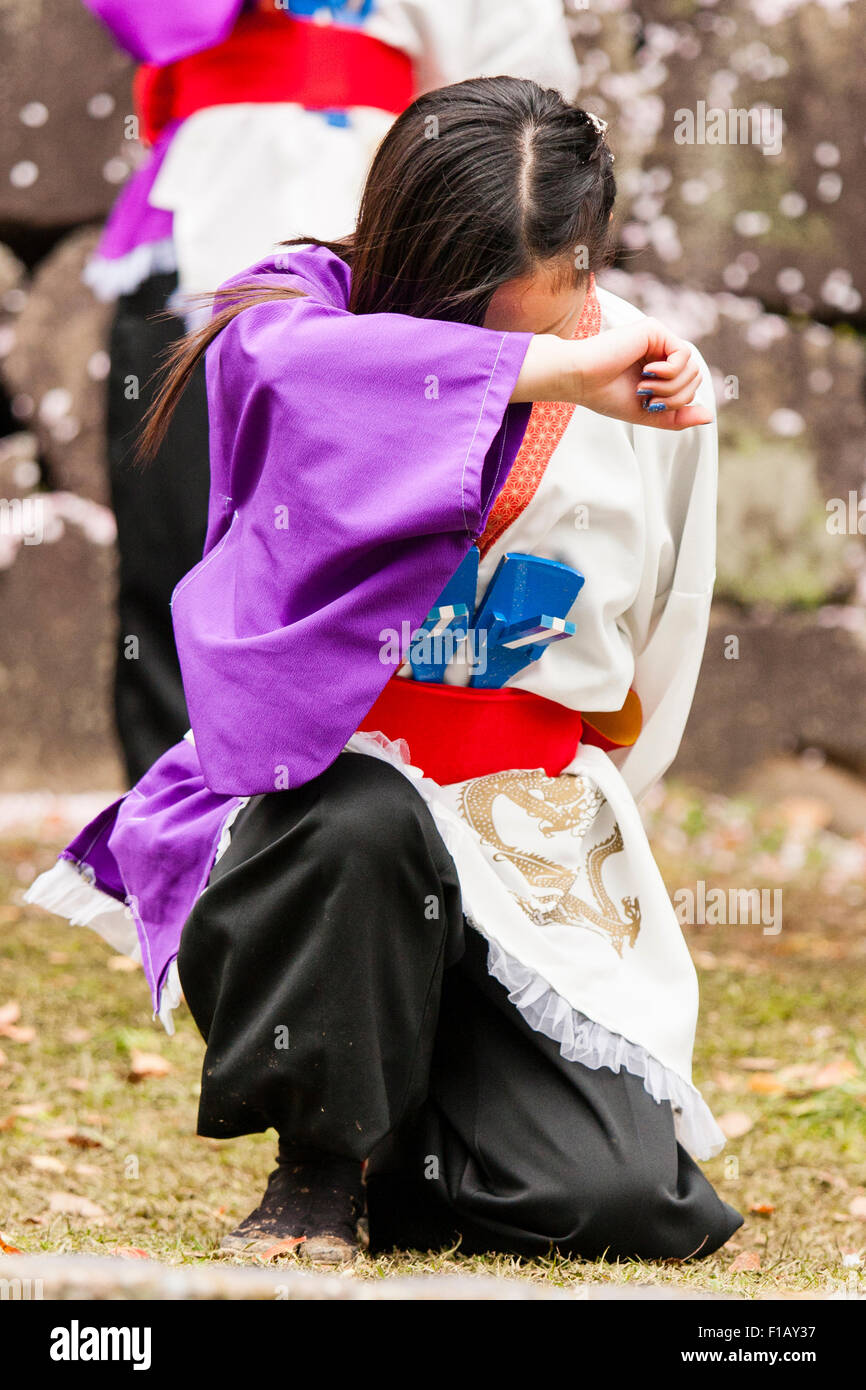 Japanische yosakoi Tanz. Zwei Mädchen im Teenager-Alter, sowohl für ihre Gesichter mit Arm, bereit, dance Routine zu starten. Vor einem kniet während andere steht. Stockfoto