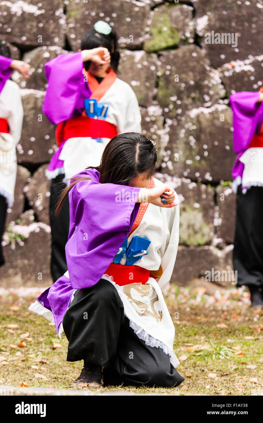Japanische yosakoi Tanz. Zwei Mädchen im Teenager-Alter, sowohl für ihre Gesichter mit Arm, bereit, dance Routine zu starten. Vor einem kniet während andere steht. Stockfoto