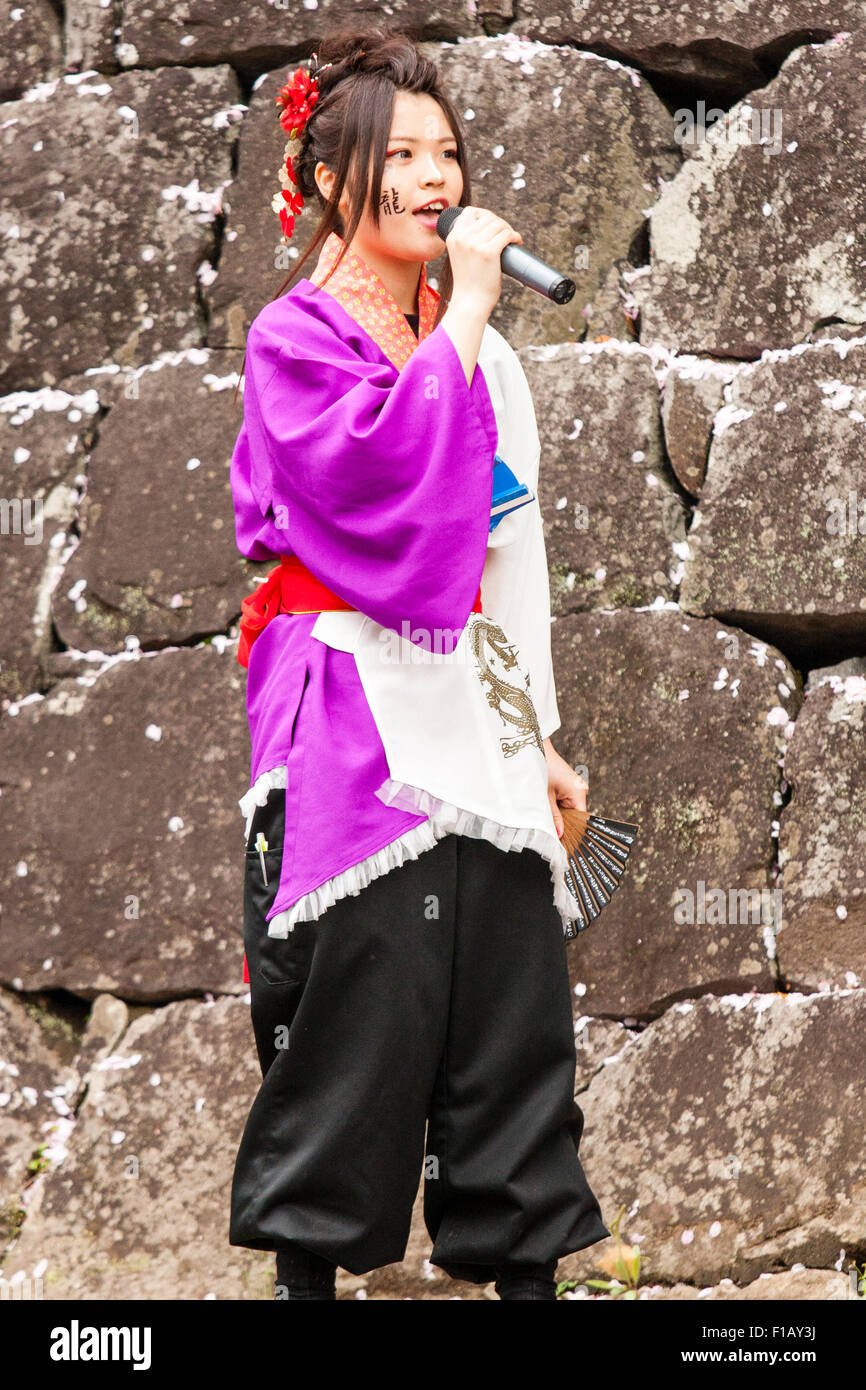 Yosakoi Dance Festival in Japan. Junges Mädchen in Lila und Weiß yukata Jacke, Teil der Dance Troupe, allein sprechen in das Mikrofon in der Hand gehalten. Stockfoto