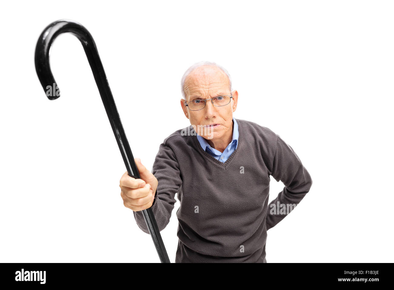 Missfallen senior hält einen schwarzen Stock und schimpfte jemand in Richtung der Kamera isoliert auf weißem Hintergrund Stockfoto